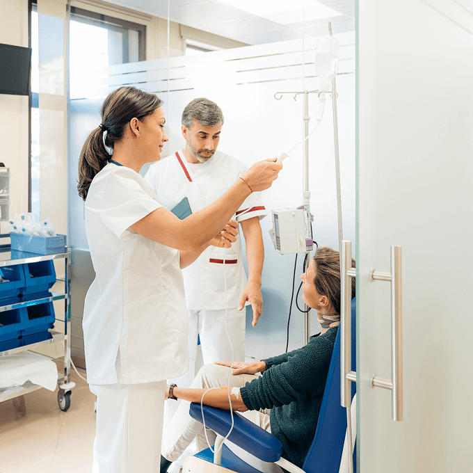 Two healthcare professionals attend to a seated patient receiving intravenous treatment in a clinic near Horizon Uptown, one of the vibrant aurora co new home communities.